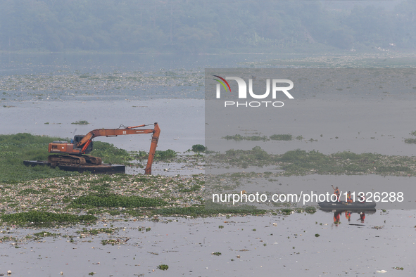 Officers are using an excavator to clean up plastic waste that has settled in the Citarum River in Batujajar, Bandung, West Java, Indonesia,...