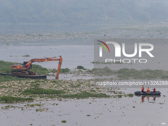 Officers are using an excavator to clean up plastic waste that has settled in the Citarum River in Batujajar, Bandung, West Java, Indonesia,...