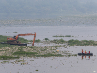 Officers are using an excavator to clean up plastic waste that has settled in the Citarum River in Batujajar, Bandung, West Java, Indonesia,...