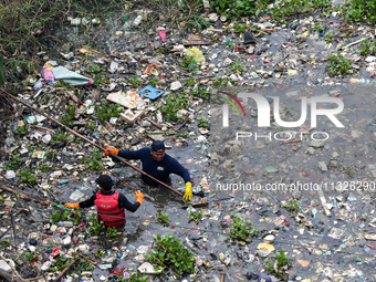 Officers are cleaning up plastic waste that has settled in the Citarum River, Batujajar, Bandung, West Java, Indonesia, on Thursday, June 13...