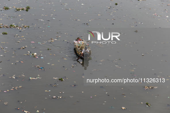 A resident is using a wooden boat to clean plastic waste that has settled in the Citarum River in Batujajar, Bandung, West Java, Indonesia,...