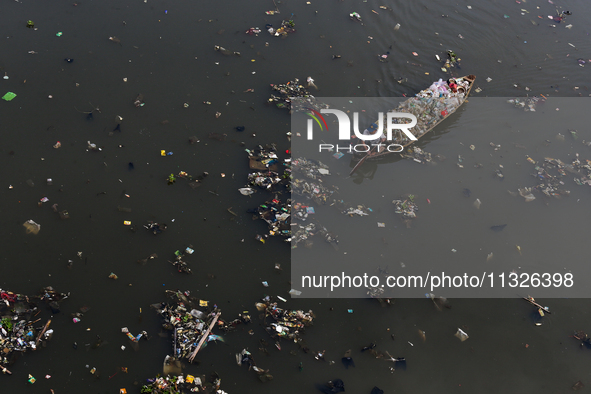 A resident is using a wooden boat to clean plastic waste that has settled in the Citarum River in Batujajar, Bandung, West Java, Indonesia,...