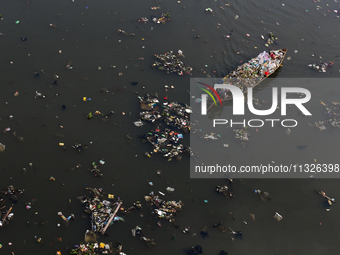 A resident is using a wooden boat to clean plastic waste that has settled in the Citarum River in Batujajar, Bandung, West Java, Indonesia,...