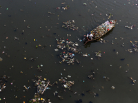 A resident is using a wooden boat to clean plastic waste that has settled in the Citarum River in Batujajar, Bandung, West Java, Indonesia,...