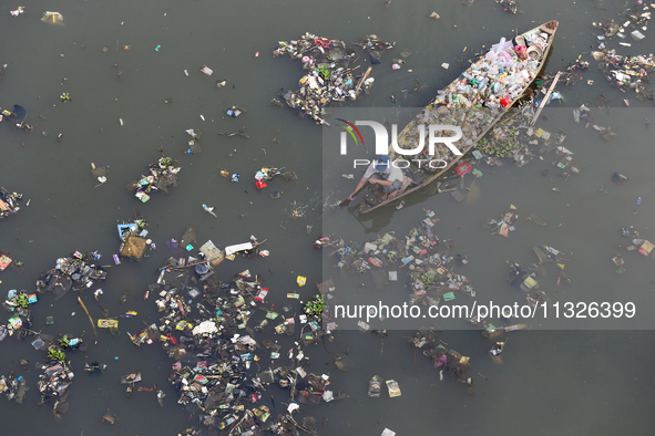 A resident is using a wooden boat to clean plastic waste that has settled in the Citarum River in Batujajar, Bandung, West Java, Indonesia,...