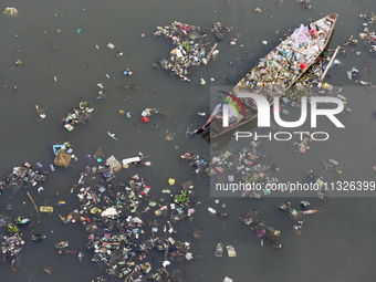 A resident is using a wooden boat to clean plastic waste that has settled in the Citarum River in Batujajar, Bandung, West Java, Indonesia,...