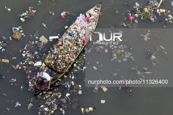 A resident is using a wooden boat to clean plastic waste that has settled in the Citarum River in Batujajar, Bandung, West Java, Indonesia,...