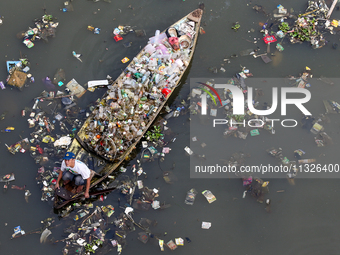 A resident is using a wooden boat to clean plastic waste that has settled in the Citarum River in Batujajar, Bandung, West Java, Indonesia,...