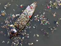 A resident is using a wooden boat to clean plastic waste that has settled in the Citarum River in Batujajar, Bandung, West Java, Indonesia,...