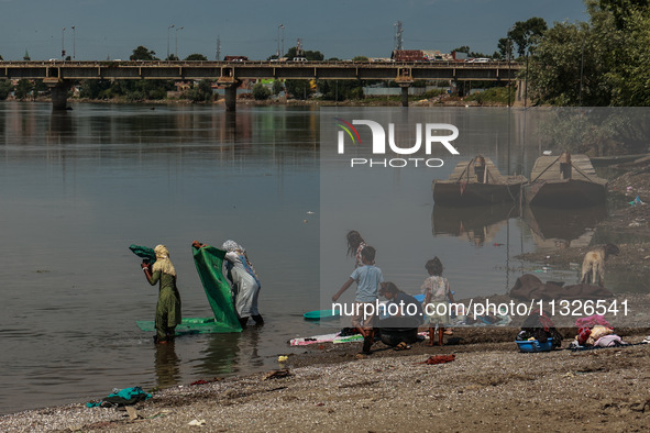 Women are washing clothes on the banks of River Jhelum on a hot summer day in Sopore, Jammu and Kashmir, India, on June 13, 2024. 