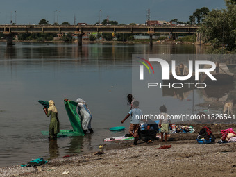 Women are washing clothes on the banks of River Jhelum on a hot summer day in Sopore, Jammu and Kashmir, India, on June 13, 2024. (