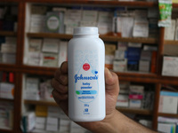 A man is holding a bottle of Johnson and Johnson Baby Powder at a drugstore in Srinagar, India, on June 13, 2024. Johnson & Johnson is agree...