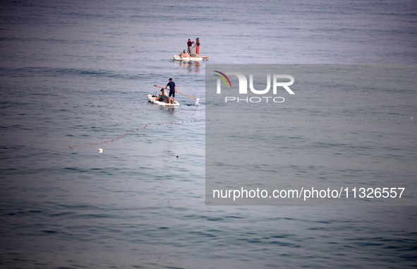 Palestinian fishermen are sailing on a boat in Deir el-Balah, in the central Gaza Strip, on June 13, 2024, amid the ongoing conflict in the...