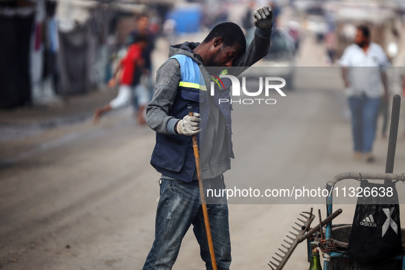 United Nations Agency for Palestinian Refugees (UNRWA) workers are cleaning a street in Deir el-Balah, in the central Gaza Strip, on June 13...