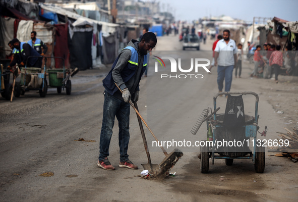 United Nations Agency for Palestinian Refugees (UNRWA) workers are cleaning a street in Deir el-Balah, in the central Gaza Strip, on June 13...