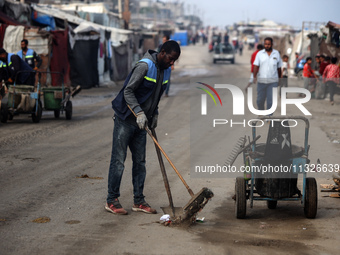 United Nations Agency for Palestinian Refugees (UNRWA) workers are cleaning a street in Deir el-Balah, in the central Gaza Strip, on June 13...