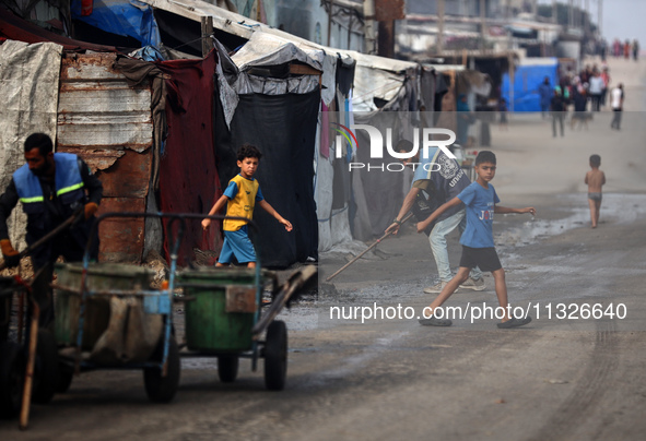 United Nations Agency for Palestinian Refugees (UNRWA) workers are cleaning a street in Deir el-Balah, in the central Gaza Strip, on June 13...