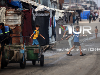 United Nations Agency for Palestinian Refugees (UNRWA) workers are cleaning a street in Deir el-Balah, in the central Gaza Strip, on June 13...