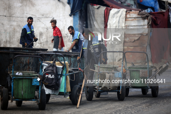 United Nations Agency for Palestinian Refugees (UNRWA) workers are cleaning a street in Deir el-Balah, in the central Gaza Strip, on June 13...