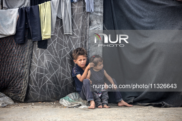 Displaced Palestinian children are sitting in front of their tent in Deir el-Balah, in the central Gaza Strip, on June 13, 2024, amid the on...