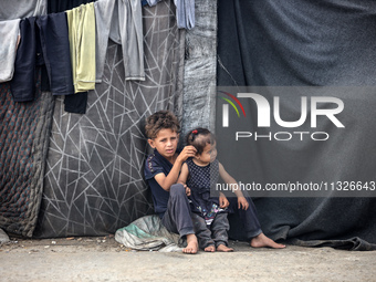 Displaced Palestinian children are sitting in front of their tent in Deir el-Balah, in the central Gaza Strip, on June 13, 2024, amid the on...