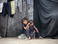 Displaced Palestinian children are sitting in front of their tent in Deir el-Balah, in the central Gaza Strip, on June 13, 2024, amid the on...