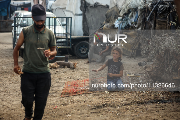 Displaced Palestinian children are sitting in front of their tent in Deir el-Balah, in the central Gaza Strip, on June 13, 2024, amid the on...