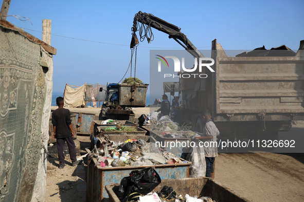 United Nations Agency for Palestinian Refugees (UNRWA) workers are cleaning a street in Deir el-Balah, in the central Gaza Strip, on June 13...