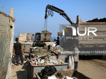 United Nations Agency for Palestinian Refugees (UNRWA) workers are cleaning a street in Deir el-Balah, in the central Gaza Strip, on June 13...