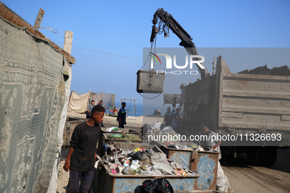 United Nations Agency for Palestinian Refugees (UNRWA) workers are cleaning a street in Deir el-Balah, in the central Gaza Strip, on June 13...