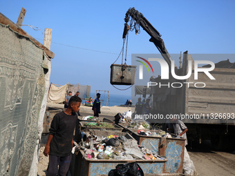 United Nations Agency for Palestinian Refugees (UNRWA) workers are cleaning a street in Deir el-Balah, in the central Gaza Strip, on June 13...