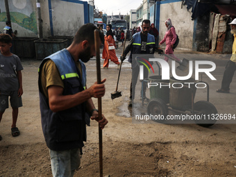 United Nations Agency for Palestinian Refugees (UNRWA) workers are cleaning a street in Deir el-Balah, in the central Gaza Strip, on June 13...