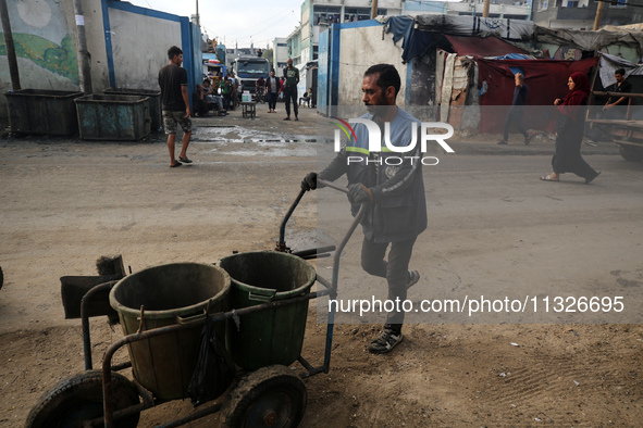 United Nations Agency for Palestinian Refugees (UNRWA) workers are cleaning a street in Deir el-Balah, in the central Gaza Strip, on June 13...