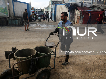 United Nations Agency for Palestinian Refugees (UNRWA) workers are cleaning a street in Deir el-Balah, in the central Gaza Strip, on June 13...