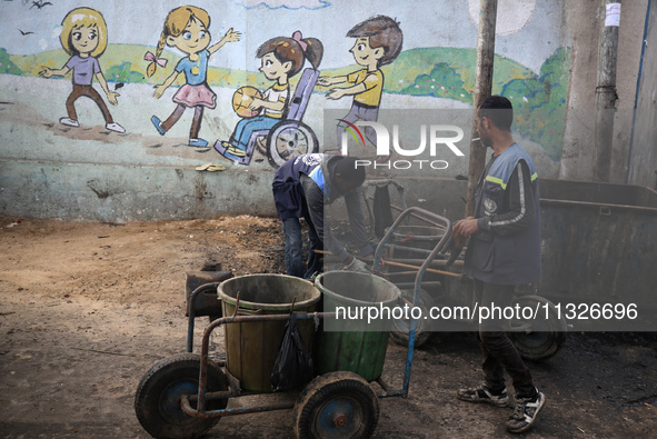 United Nations Agency for Palestinian Refugees (UNRWA) workers are cleaning a street in Deir el-Balah, in the central Gaza Strip, on June 13...