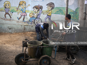 United Nations Agency for Palestinian Refugees (UNRWA) workers are cleaning a street in Deir el-Balah, in the central Gaza Strip, on June 13...