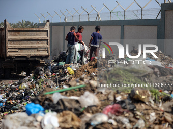 Displaced Palestinian children are searching for recyclables at a garbage dump in Deir el-Balah, in the central Gaza Strip, on June 13, 2024...