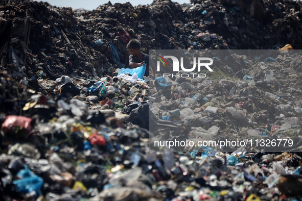 A Palestinian boy is searching for recyclables at a garbage dump in Deir el-Balah, in the central Gaza Strip, on June 13, 2024, amid the ong...