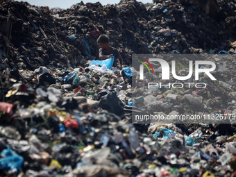 A Palestinian boy is searching for recyclables at a garbage dump in Deir el-Balah, in the central Gaza Strip, on June 13, 2024, amid the ong...