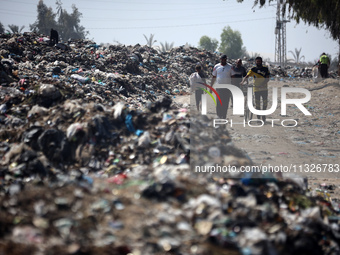 Palestinians are walking next to a garbage dump in Deir el-Balah, in the central Gaza Strip, on June 13, 2024, amid the ongoing conflict in...