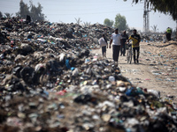 Palestinians are walking next to a garbage dump in Deir el-Balah, in the central Gaza Strip, on June 13, 2024, amid the ongoing conflict in...