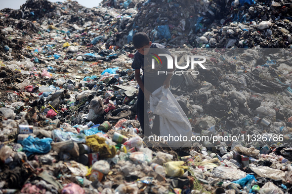 A Palestinian boy is searching for recyclables at a garbage dump in Deir el-Balah, in the central Gaza Strip, on June 13, 2024, amid the ong...