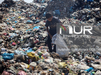 A Palestinian boy is searching for recyclables at a garbage dump in Deir el-Balah, in the central Gaza Strip, on June 13, 2024, amid the ong...