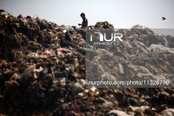 A Palestinian boy is searching for recyclables at a garbage dump in Deir el-Balah, in the central Gaza Strip, on June 13, 2024, amid the ong...