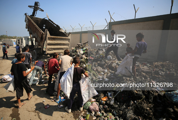 Displaced Palestinian children are searching for recyclables at a garbage dump in Deir el-Balah, in the central Gaza Strip, on June 13, 2024...