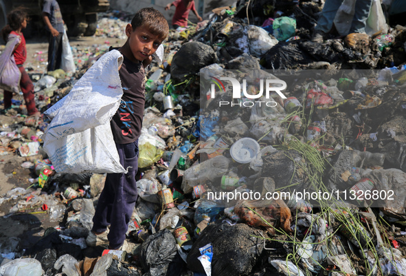 A Palestinian boy is searching for recyclables at a garbage dump in Deir el-Balah, in the central Gaza Strip, on June 13, 2024, amid the ong...