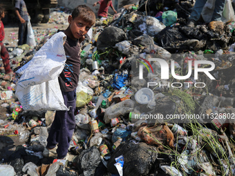 A Palestinian boy is searching for recyclables at a garbage dump in Deir el-Balah, in the central Gaza Strip, on June 13, 2024, amid the ong...