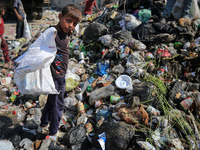 A Palestinian boy is searching for recyclables at a garbage dump in Deir el-Balah, in the central Gaza Strip, on June 13, 2024, amid the ong...