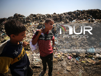 Displaced Palestinian children are searching for recyclables at a garbage dump in Deir el-Balah, in the central Gaza Strip, on June 13, 2024...