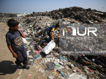 Displaced Palestinian children are searching for recyclables at a garbage dump in Deir el-Balah, in the central Gaza Strip, on June 13, 2024...